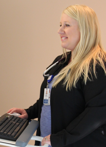 Julie Deering, APRN in black jacket and blue shirt checking patient records on computer