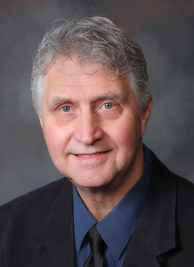 Dr. John Hart wearing suit and dark blue shirt - headshot