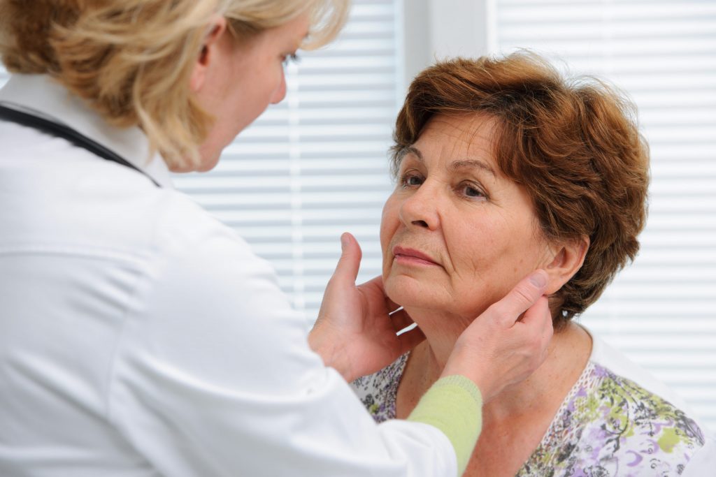 female doctor touching the throat of a patient in the office