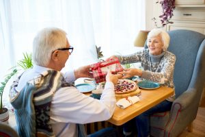 Old couple sitting at table eating dinner and exchanging gifts heart-healthy gift ideas for the one you love this Valentine's Day