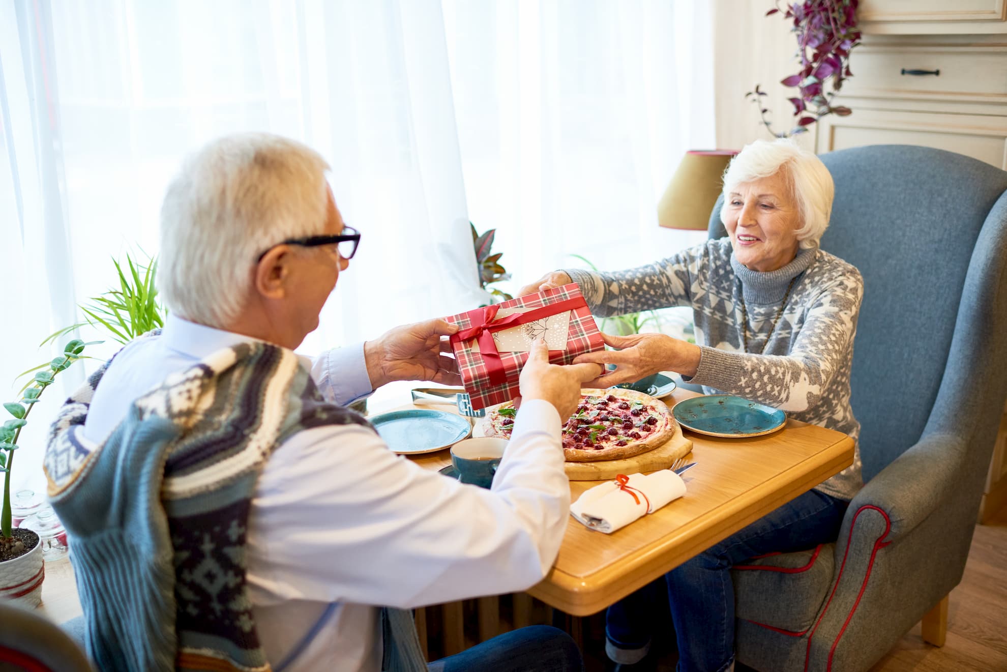 Old couple sitting at table eating dinner and exchanging gifts heart-healthy gift ideas for the one you love this Valentine's Day