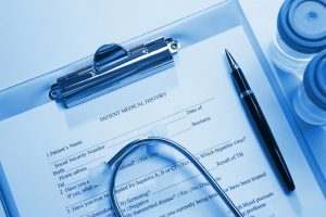 clipboard of patient records with specimen cup and pen