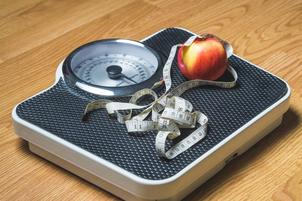 weight with measuring tape and apple sitting on top of it on the floor weight management manage your weight weight loss