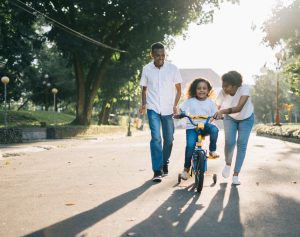 man-standing-beside-his-wife-teaching-their-child-how-to-ride-a-bike