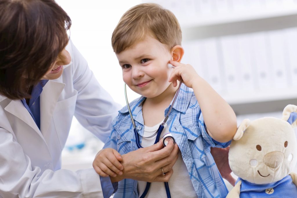 doctor letting young boy listen to his heartbeat with stethoscope at a family medicine clinic