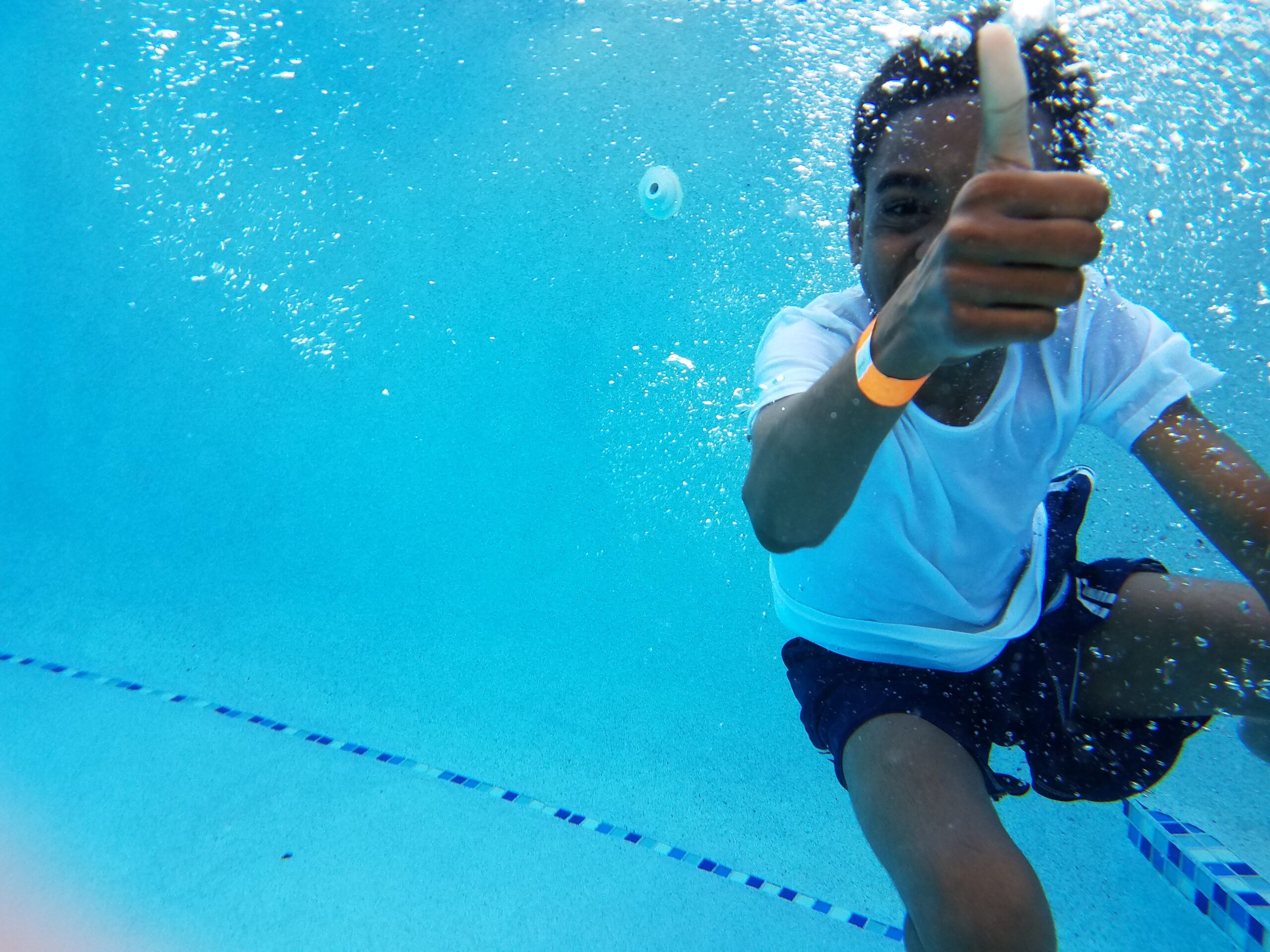black kid swimming underwater giving thumbs up for swim safety