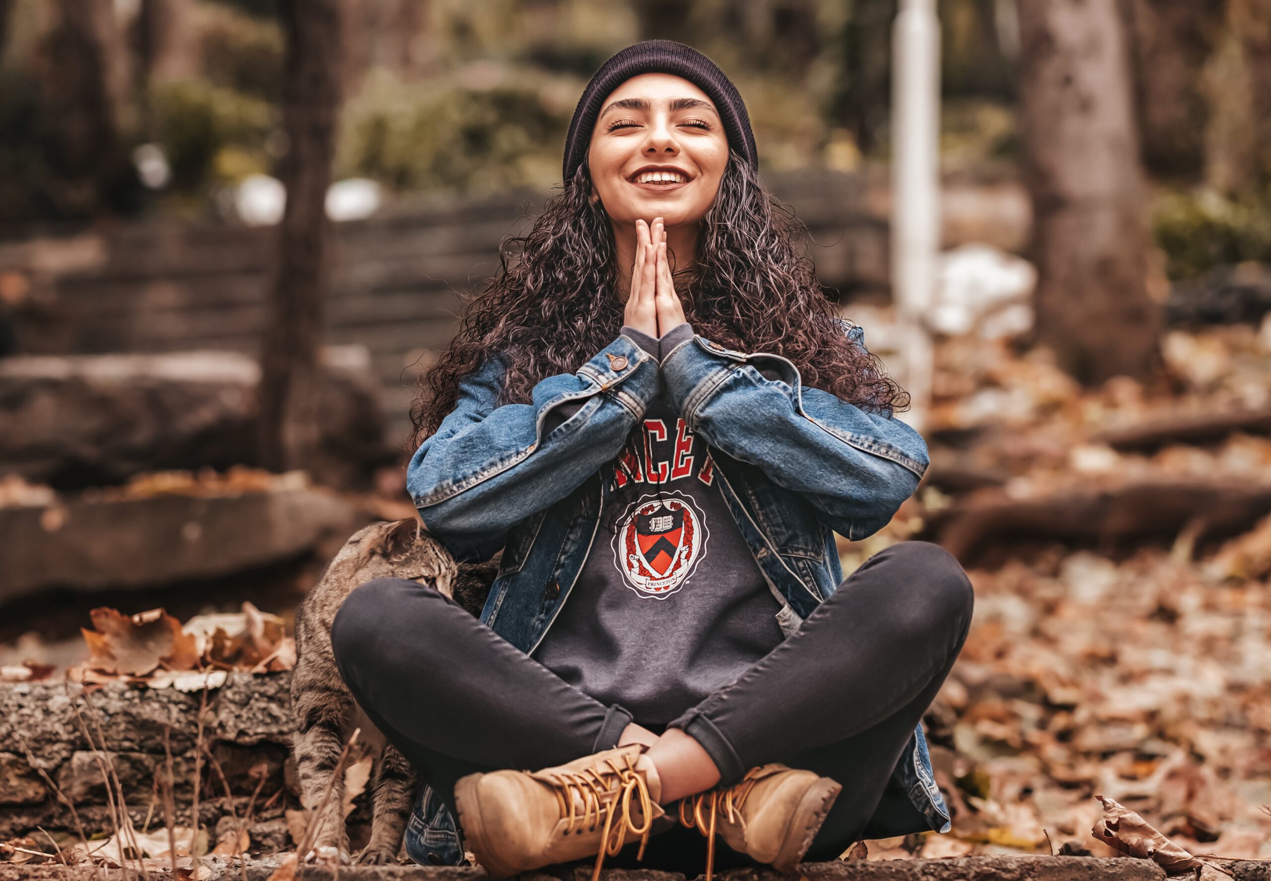 hispanic girl smiles and sits in indian style yoga pose with namaste hands