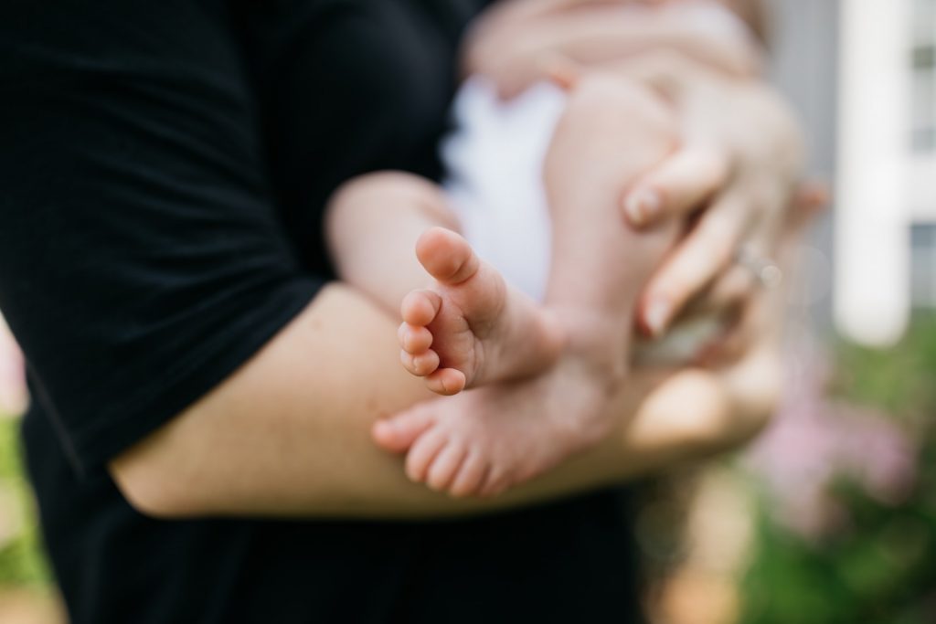 Person in black shirt holding baby with feet pointed toward camera