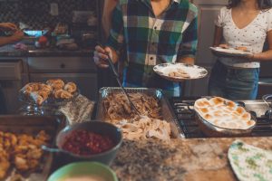 People serving themselves at a homestyle buffet for thanksgiving dinner holidays and COVID-19 precautions