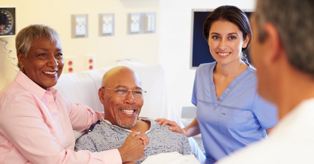NMC Health Services patients and visitors gathered around the bedside with a staff member