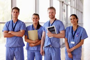 Group of young doctors or nurses in ciel blue scrubs waiting for you to contact us