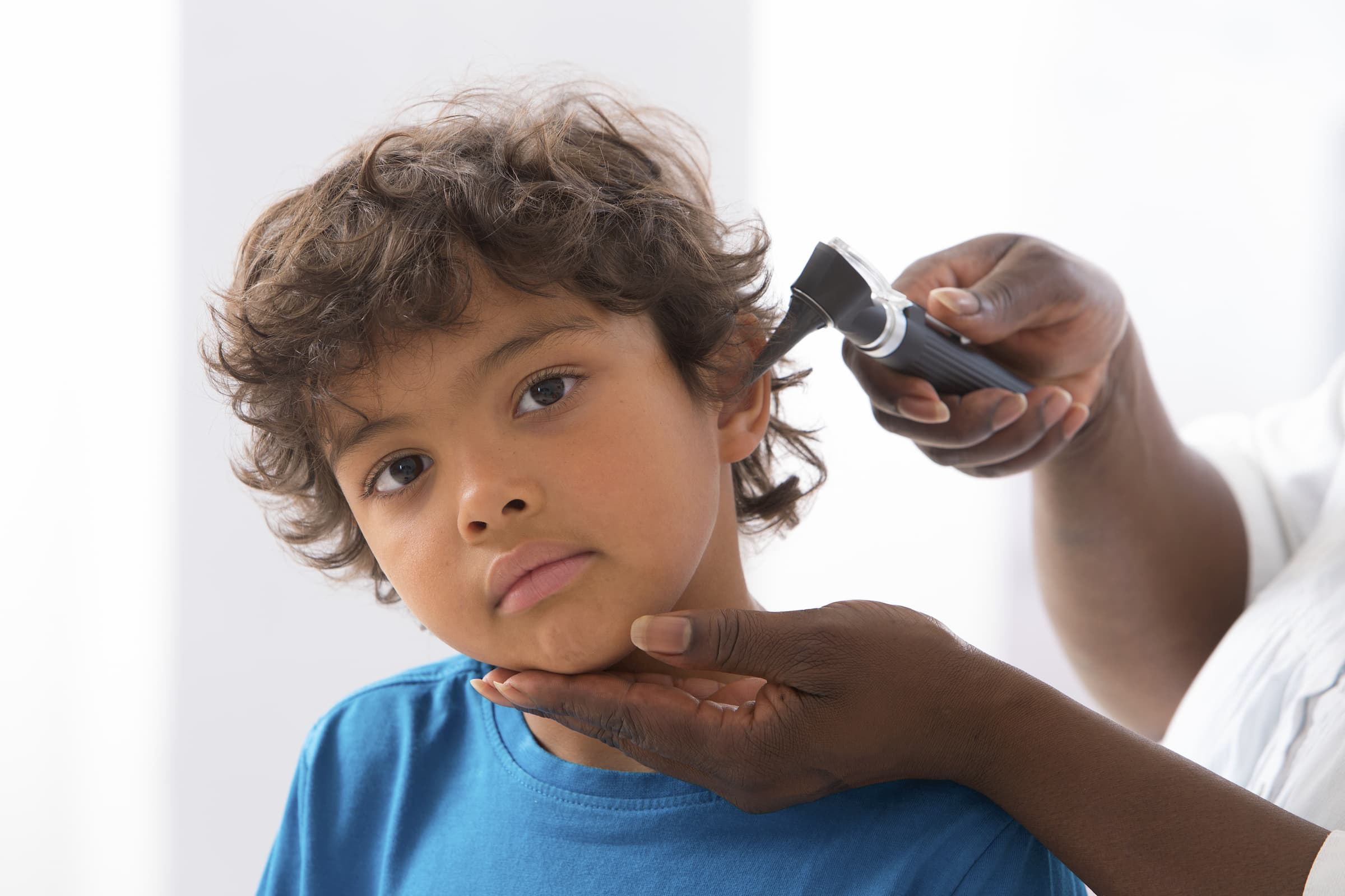 young hispanic boy getting ears checked by black doctor