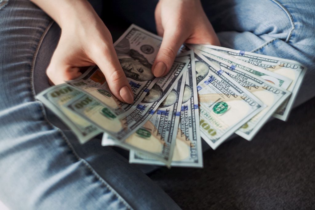 hands with several hundred dollar bills fanned out weight cost of medical care healthcare saving on medical procedures