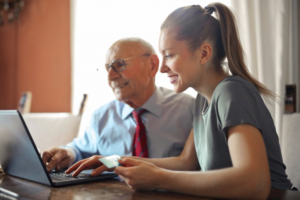 white elderly man and white woman making a payment online with a credit card at a laptop
