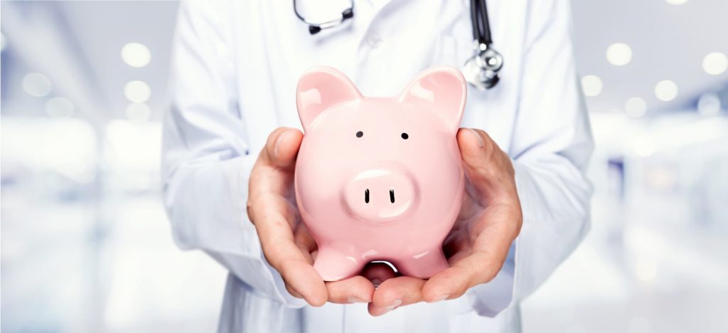 white doctor holding piggy bank in hands with stethoscope around neck - healthcare savings - healthcare costs - mdsave program