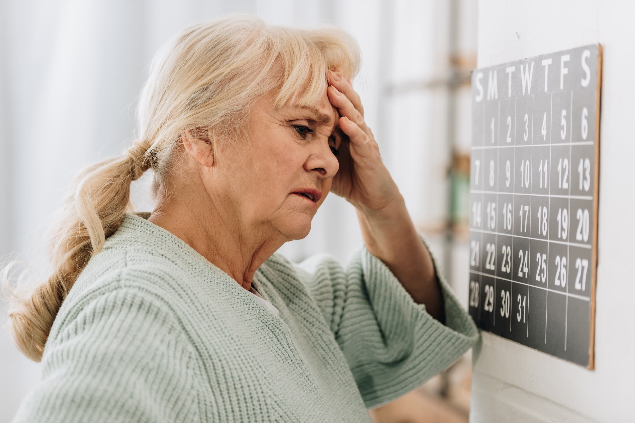 white woman holding head while looking at neurology brain scans - dementia, memory loss, neurology care