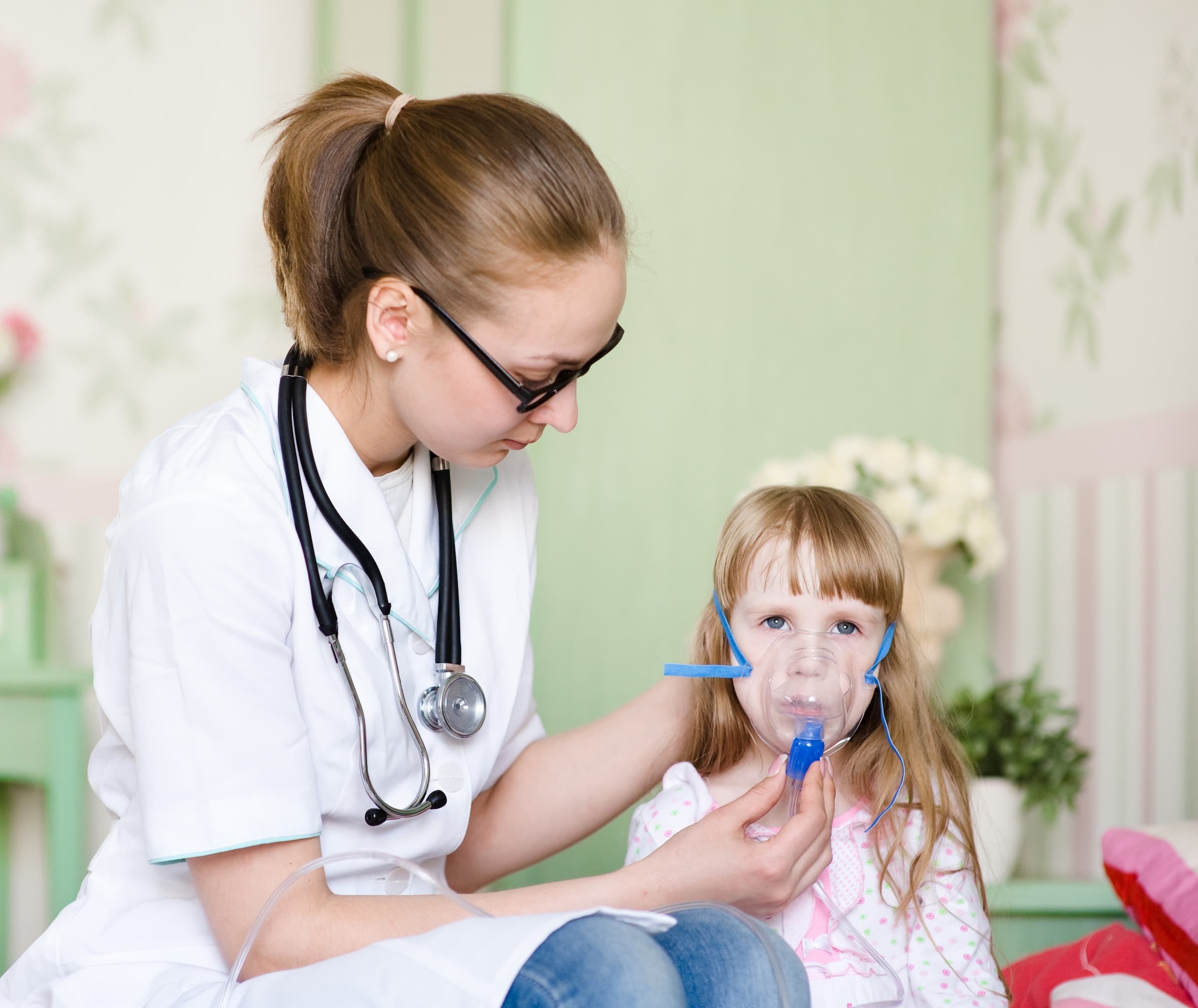 young white doctor helping white female young child breathe with nebulizer and oxygen mask during respiratory therapy session