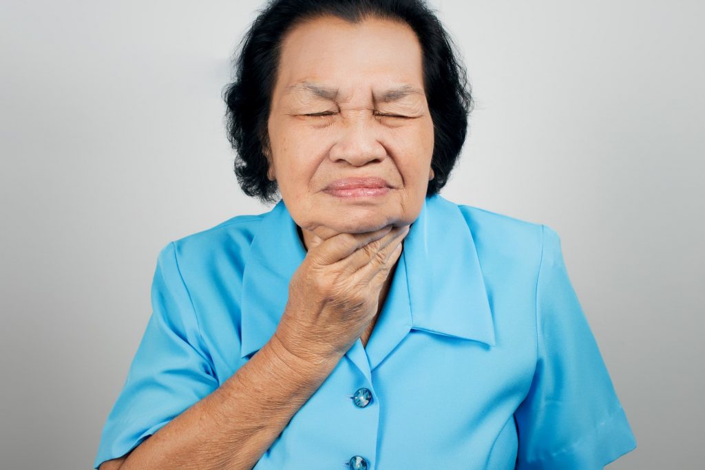 senior asian woman clutching throat for swallowing speech therapy representation