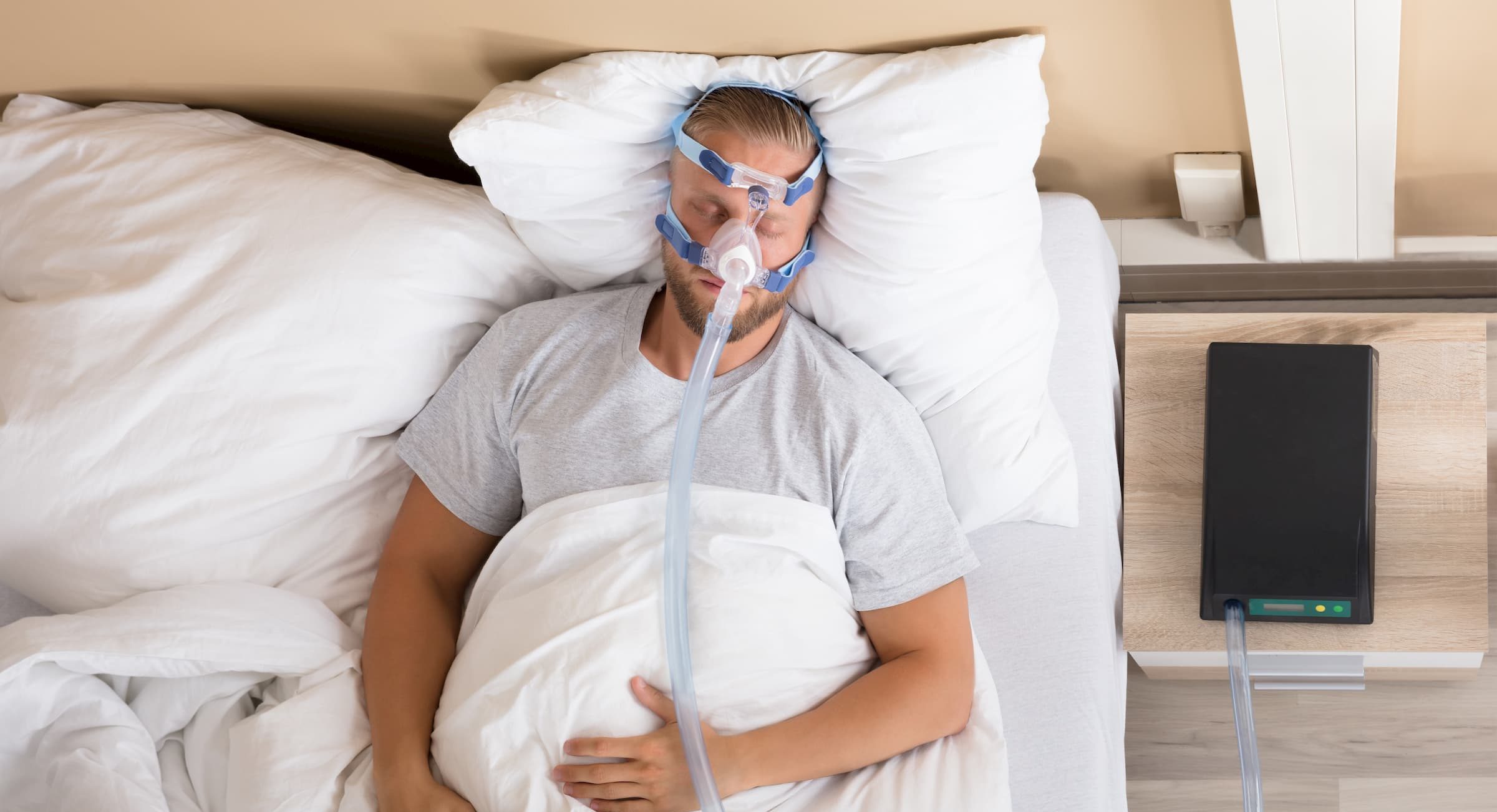 birdseye view of white man sleeping with cpap respirator over his nose for sleep medicine