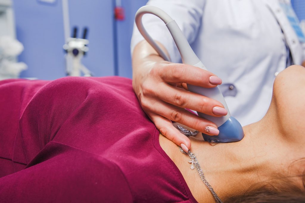 ultrasound technician performing ultrasound on woman's throat thyroid white woman patient