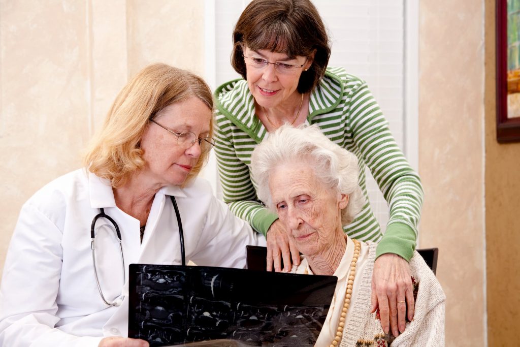 white senior woman with family and white doctor showing her brain scan talking about Alzheimer's and dementia care memory care