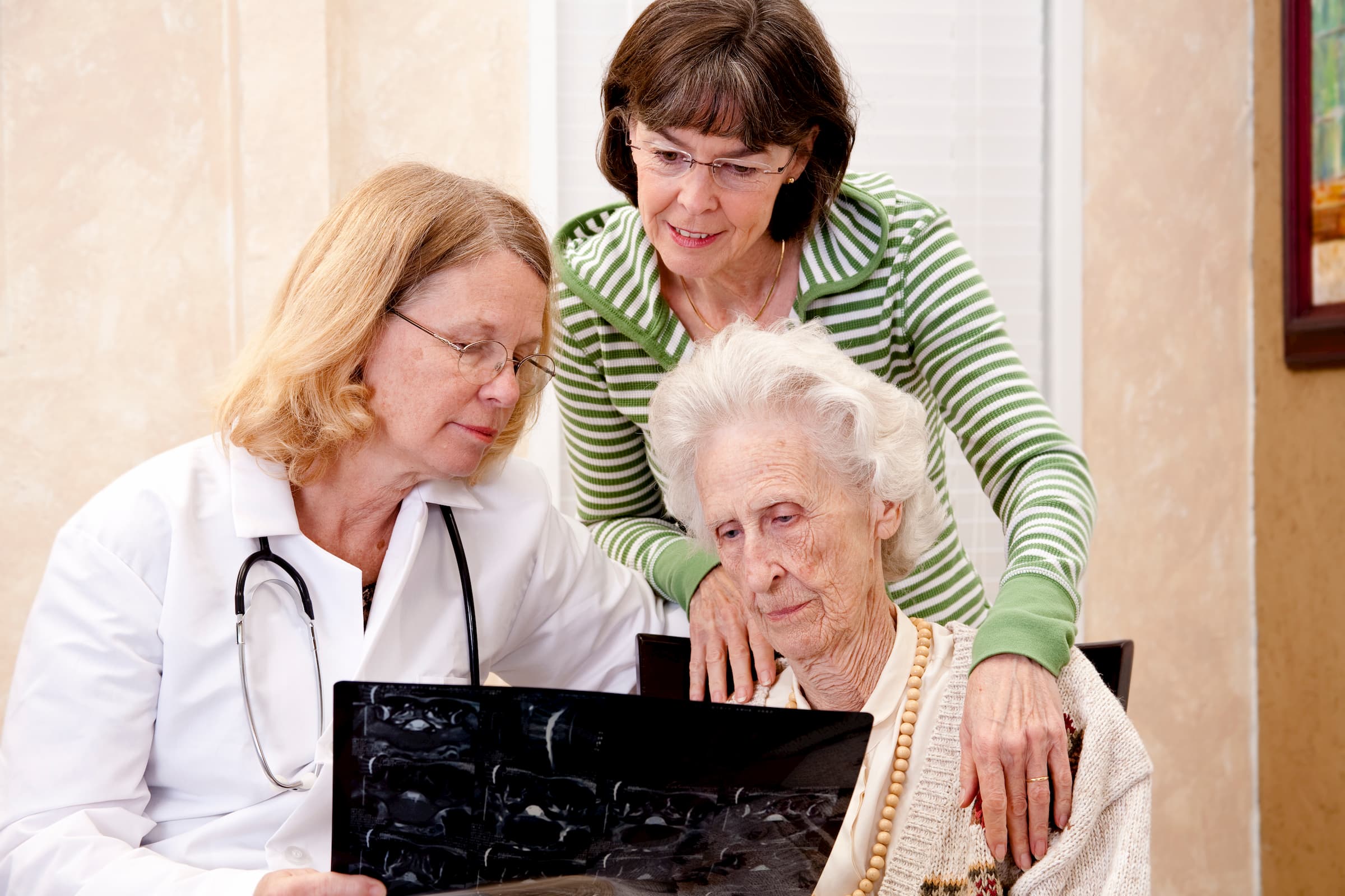 white senior woman with family and white doctor showing her brain scan talking about Alzheimer's and dementia care memory care