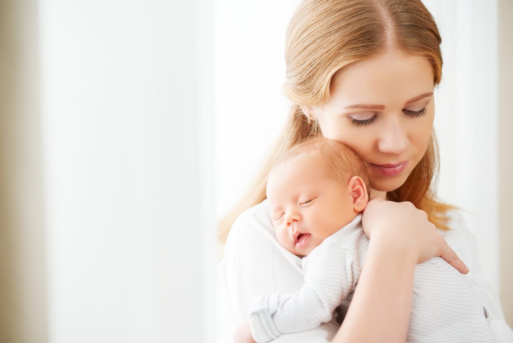 newborn baby in a tender embrace of mother at the window white mom with white baby newborn cute