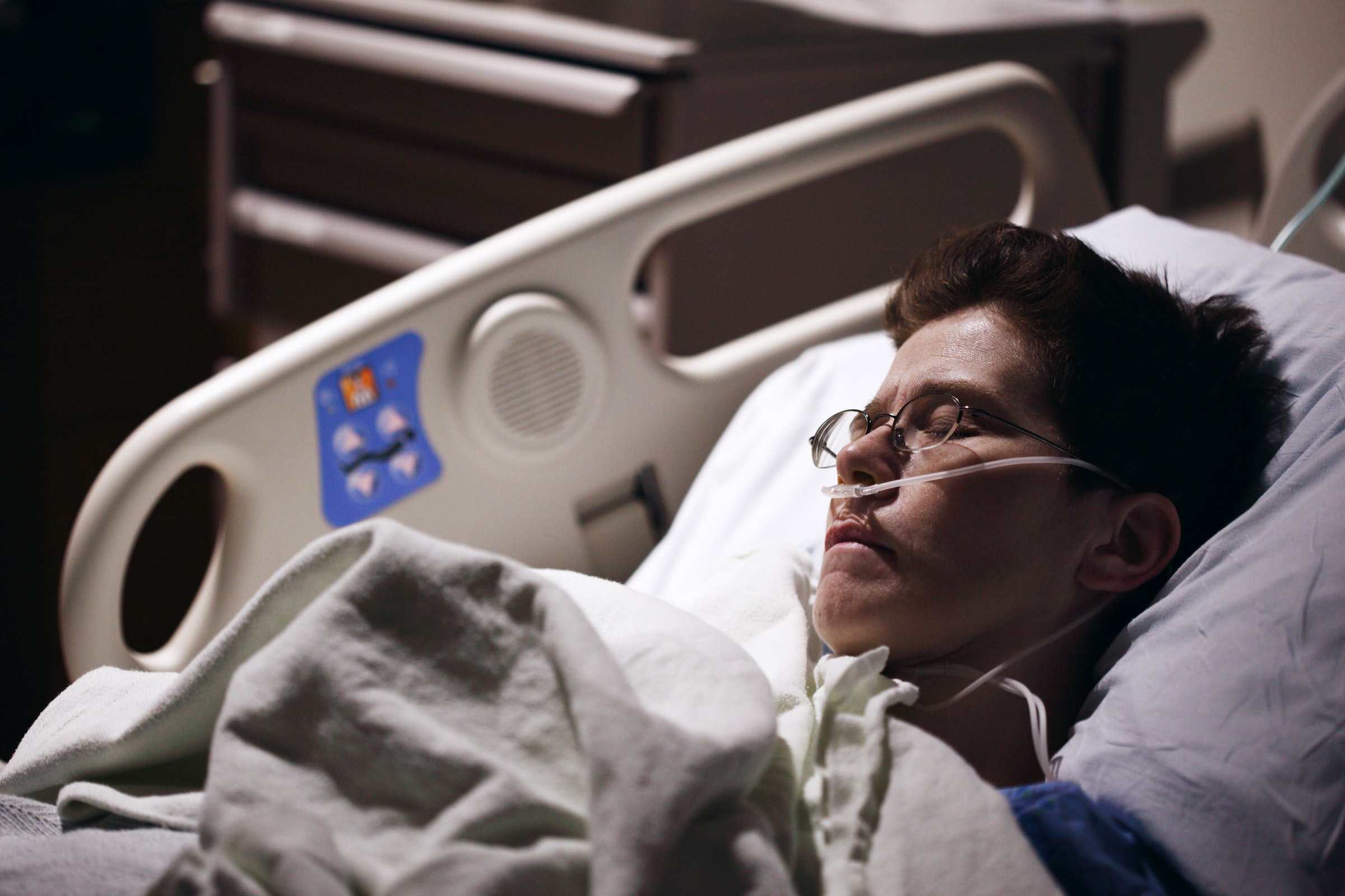 white person lying in bed with oxygen cannula in nose after surgery recovery stock photo