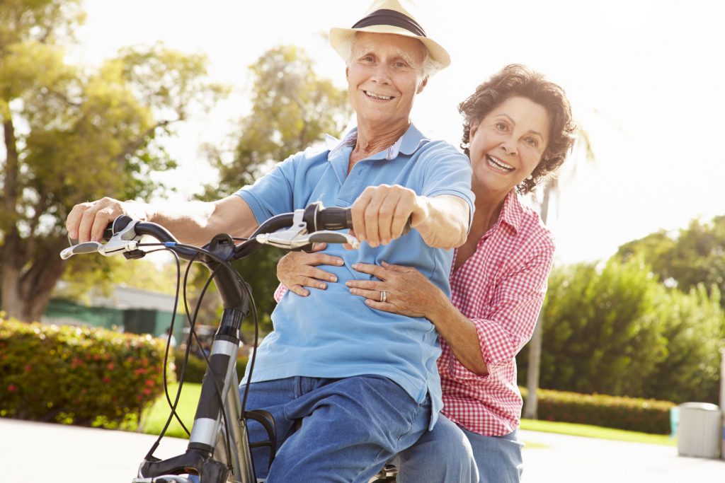 Senior Hispanic Couple Riding Bikes In Park