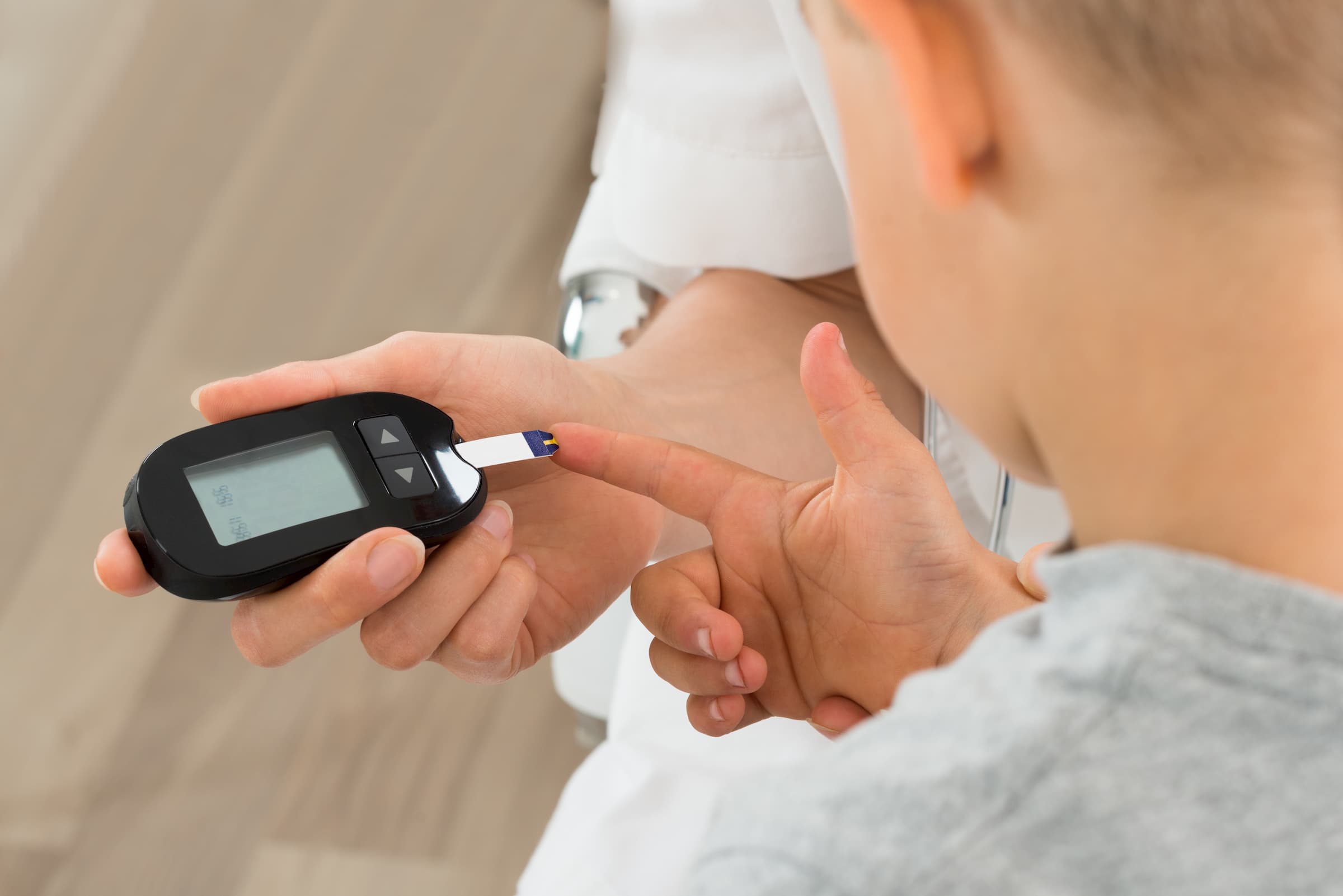 doctor helping person check blood sugar with glucose meter for diabetes management and endocrinology