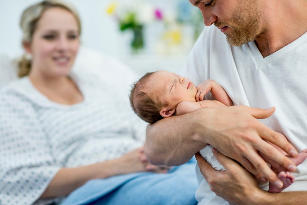 white woman who just gave birth mom and dad holding newborn baby boy in hospital stock photo