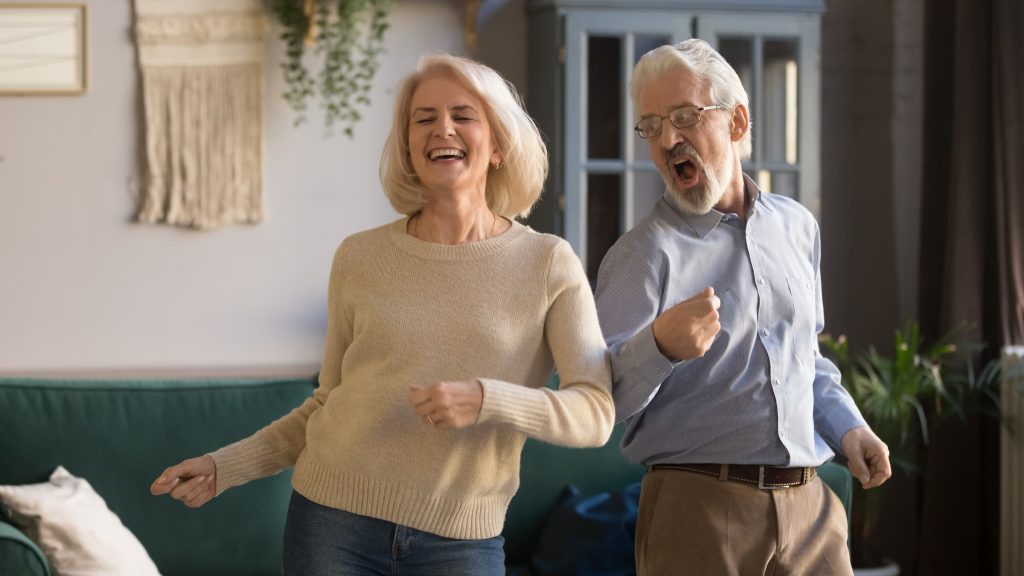 white senior couple man and woman dancing in their living room back on your feet light on your feet dancing happy couple