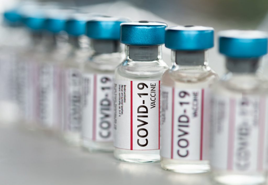 covid-19 vaccine vials lined up in a line with a focus and other vials blurred out