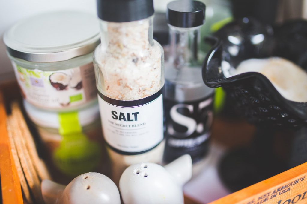 coconut oil, salt, salt shakers, morter and pestal, seasoning bottle on shelf in kitchen low sodium diet