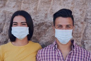 white couple smiling and standing next to each other wearing masks one woman and one man