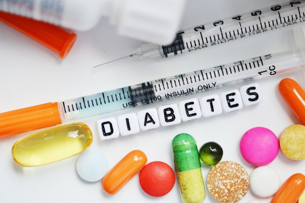diabetes medicine, pills, vitamins and other oral medicines, insulin in syringes, needles and the word diabetes in lettered beads