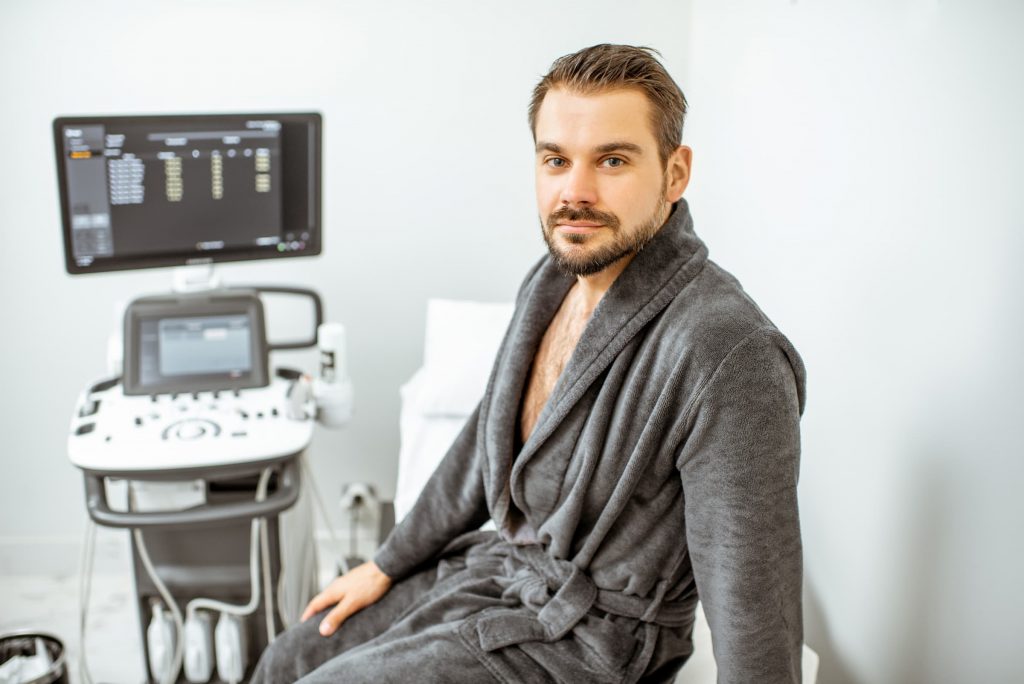 man sitting on exam room table waiting for top five tests that could save your list screening, men's health screening