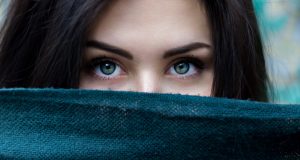 women with blue/green eyes with face obscured by blue towel