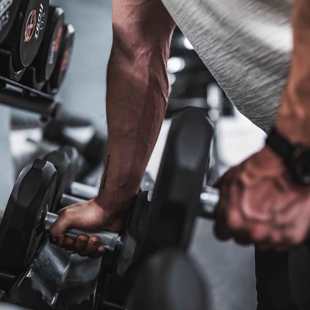 Man picks up free weights at a gym as he exercises