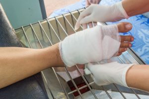 gloved hands wrap foot of patient with wound dressing