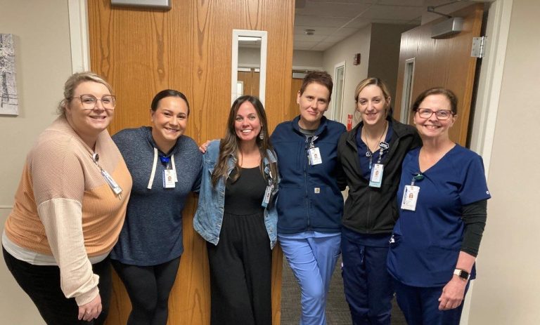 learn about nmc health and a group of smiling nurses standing huddled together to welcome applicants to open positions