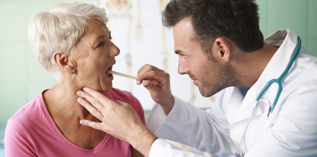 ent Doctor checking throat of senior woman