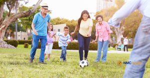 happy family of all ages playing soccer on green grass