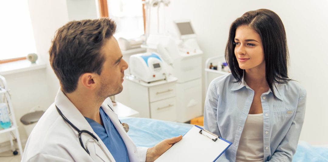 doctor speacking with patient in an exam room refering to pre-registration documents