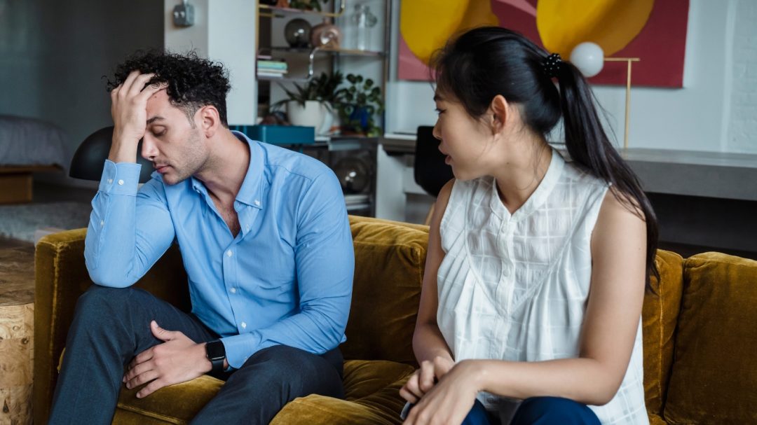 a man is holding his head and a women is looking at him to see if the B.E. F.A.S.T. signs indicate that he is experiencing a stroke