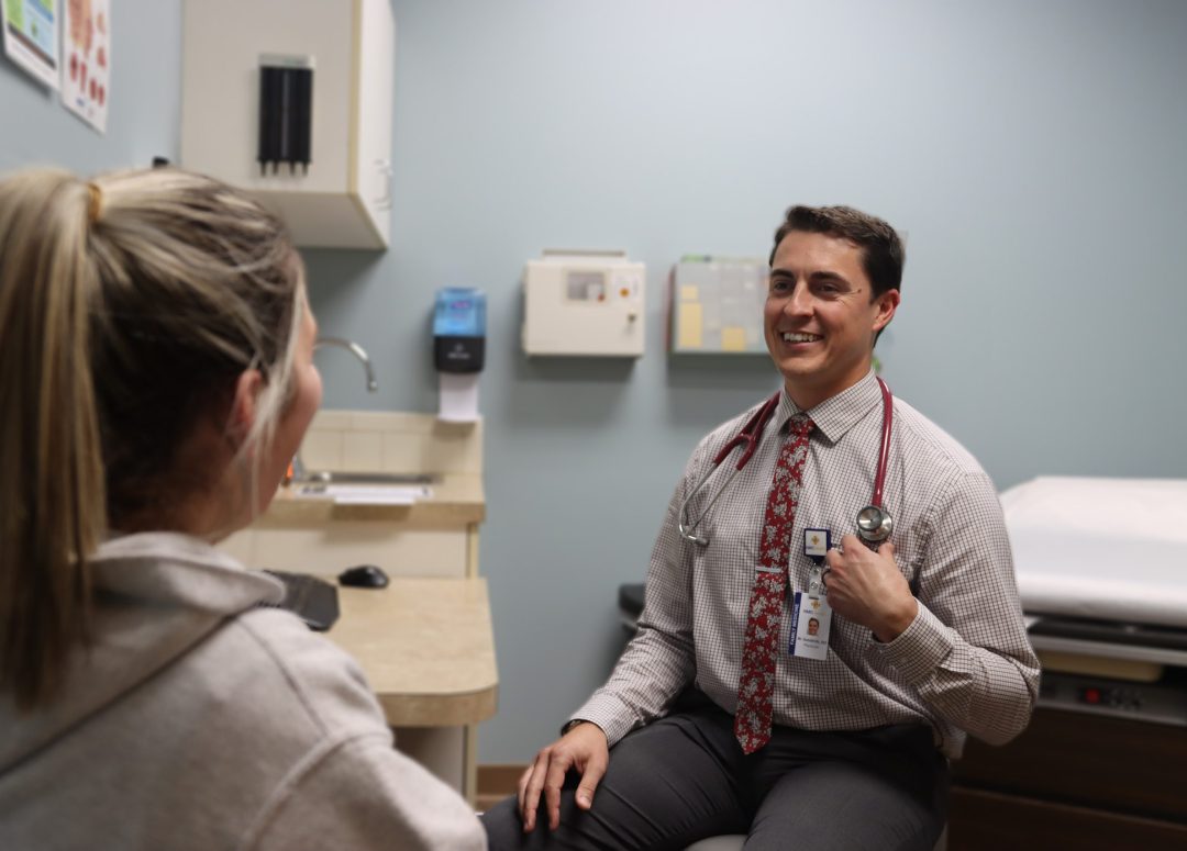 A family medicine doctor consulting a patient in an exam room for ent doctor referal