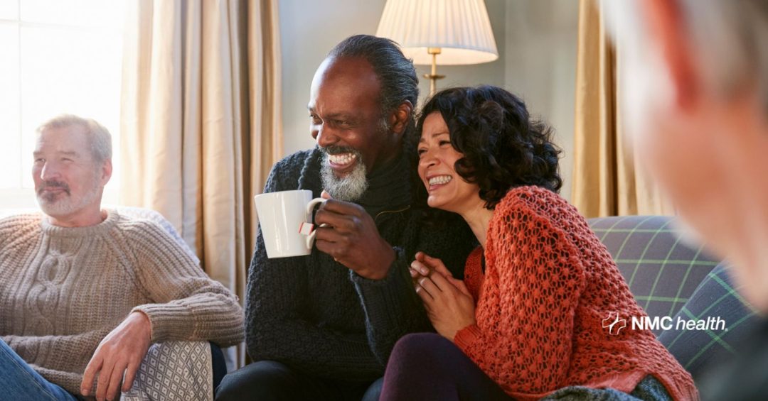 diverse couple sitting on sofa in living room smiling and laughing