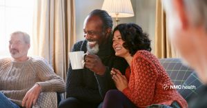 diverse couple sitting on sofa in living room smiling and laughing