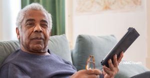 older african american man holding phone and reading glasses, while looking at camera