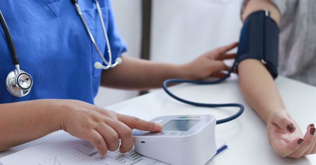 a nurse measures a patient for high blood pressure